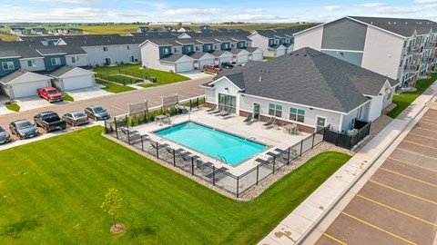 A swimming pool is surrounded by a fence in a grassy area.