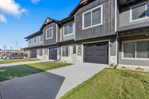 A modern two-story house with a grey exterior and a black garage door.