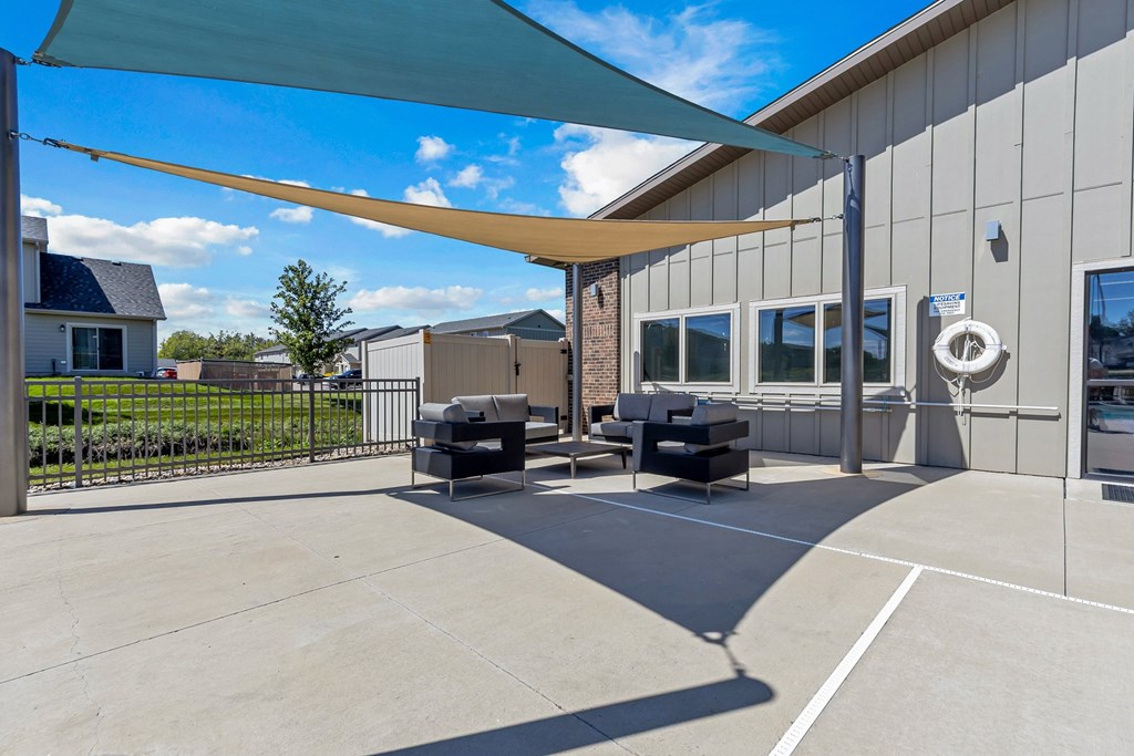 A patio area with a white wall and a black sofa.