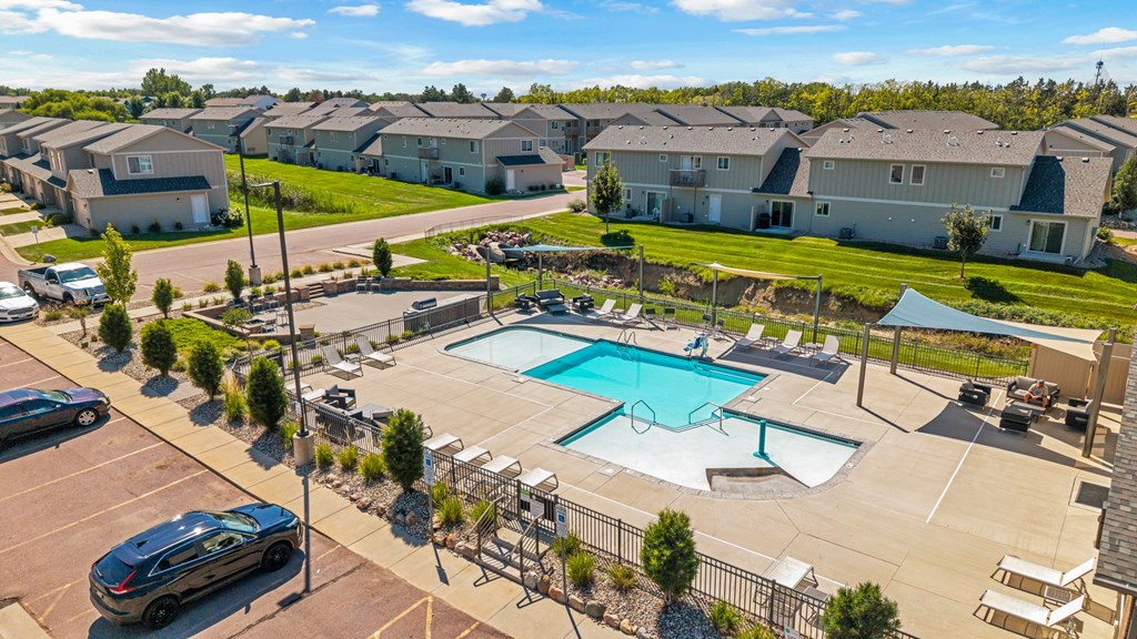 A swimming pool in a residential area surrounded by houses and cars.