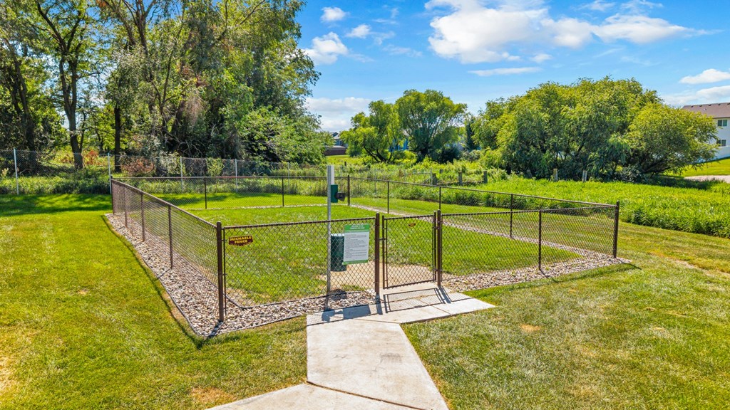 A green fenced area with a gate and a small building.
