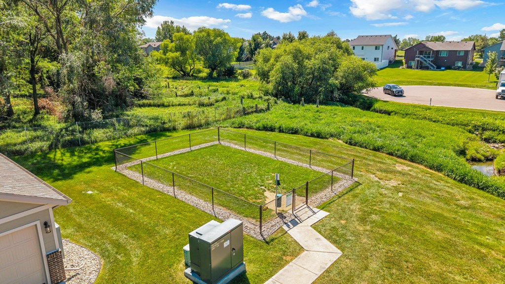 A green field with a fence and a small building in the middle.