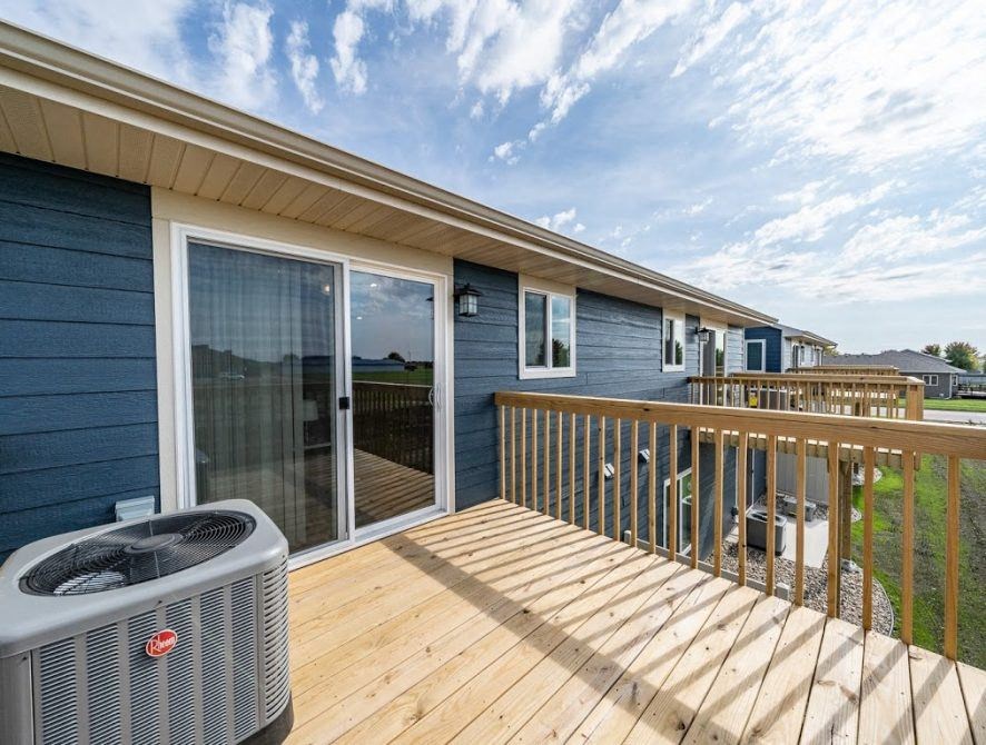 a deck with a heater on it and a blue house
