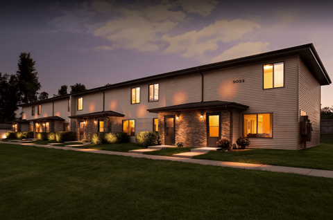 the exterior of a home at night with lights on in the windows