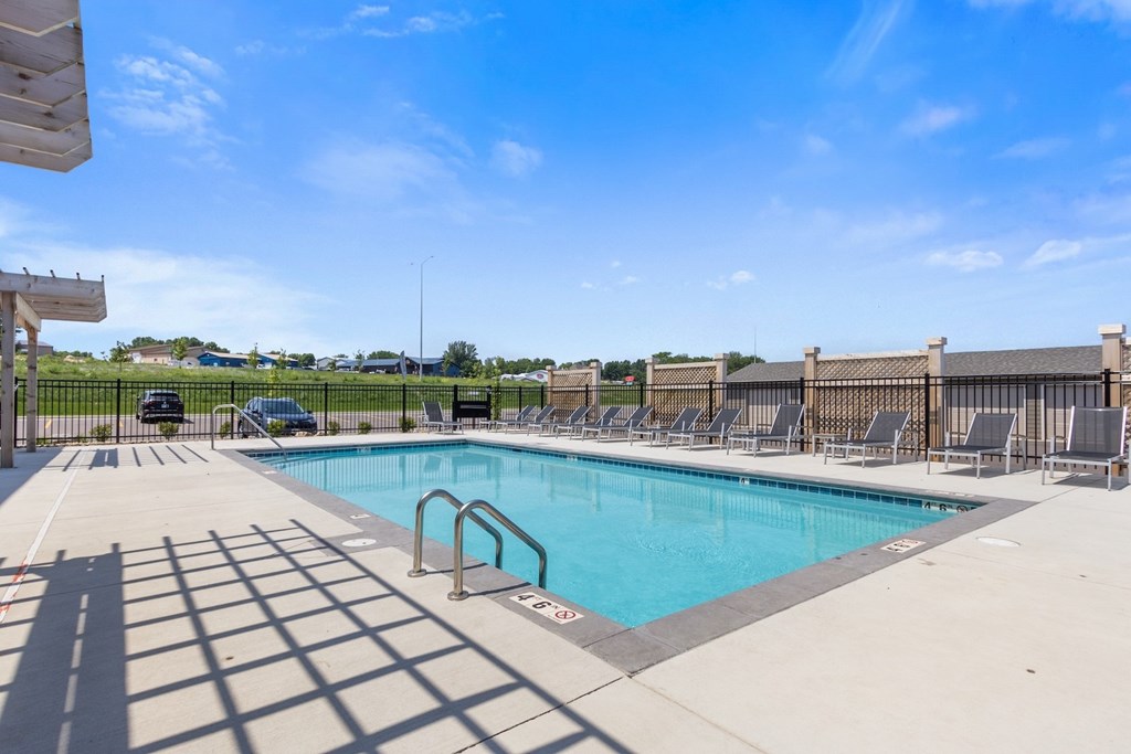 A pool surrounded by a fence and chairs.