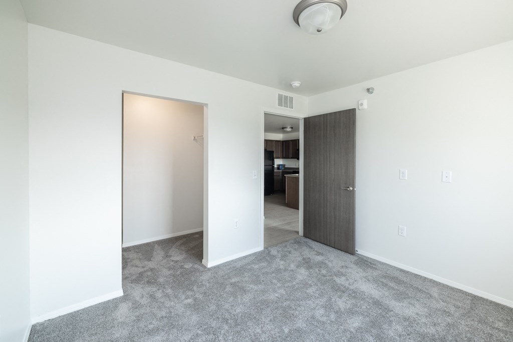 an empty living room with white walls and a door to a bedroom