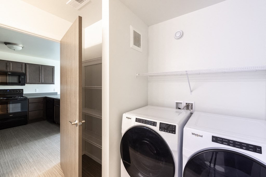 a washer and dryer in a laundry room with a kitchen in the background