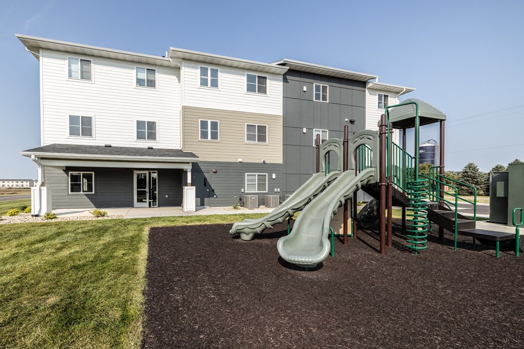 a playground with a slide in front of an apartment building