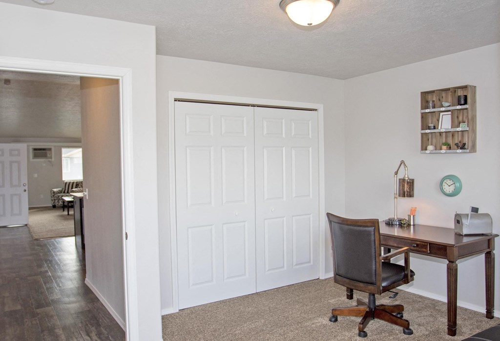 a home office with a desk and a door to a living room