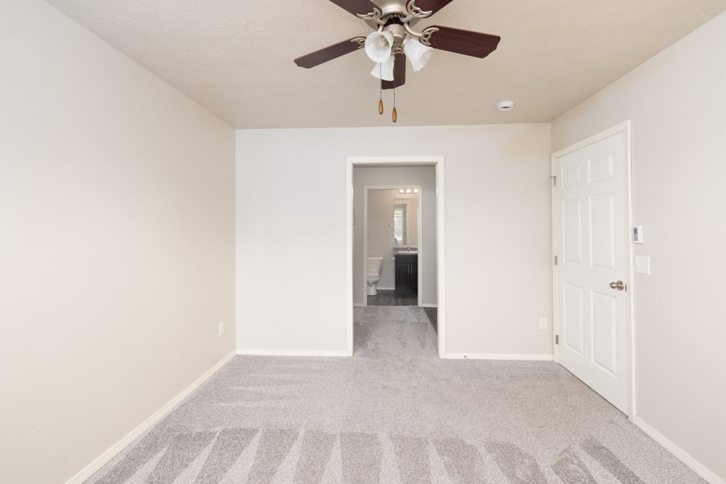 A room with a ceiling fan and a carpeted floor.