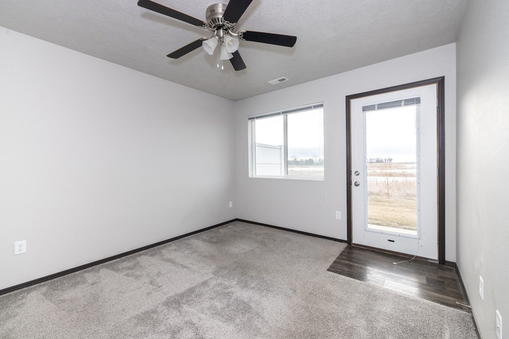 A room with a ceiling fan and a door leading outside.