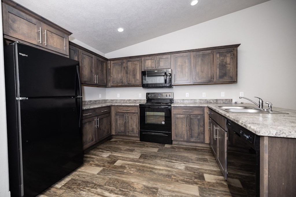 A kitchen with a black fridge and wooden cabinets.