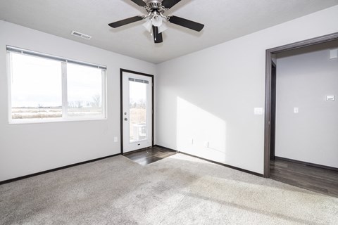 A room with a ceiling fan and a rug on the floor.