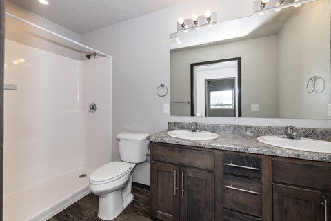 A bathroom with a toilet, sink, and mirror.
