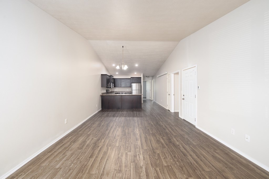 A long, empty hallway with wood flooring and white walls.