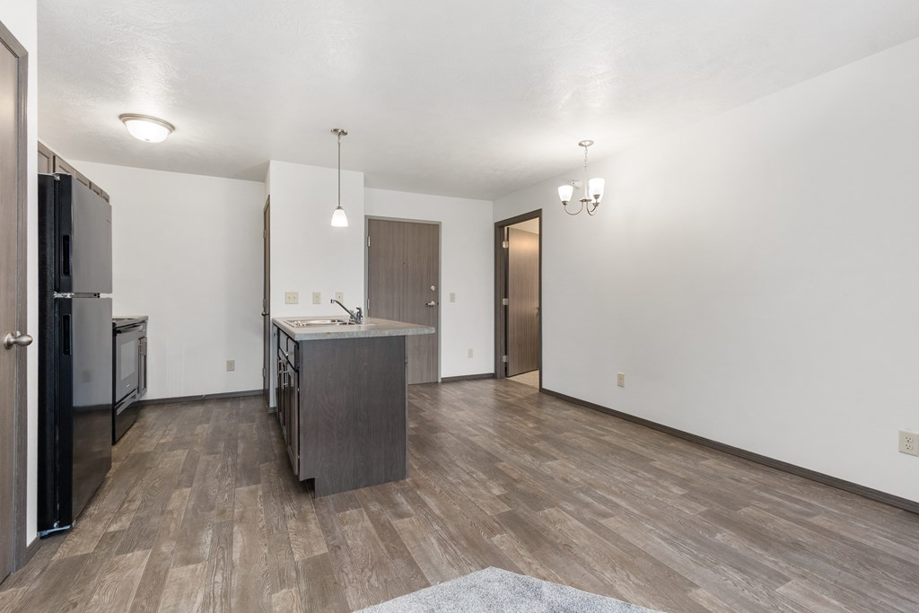 A kitchen with a refrigerator, sink, and cabinets.