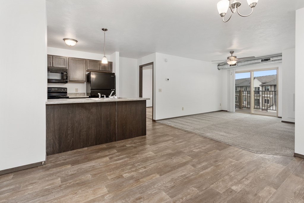 A kitchen with a wooden floor and a white wall.