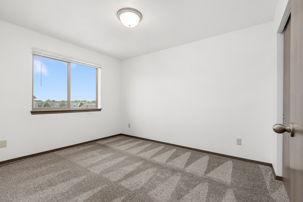 A room with a carpeted floor and a window.