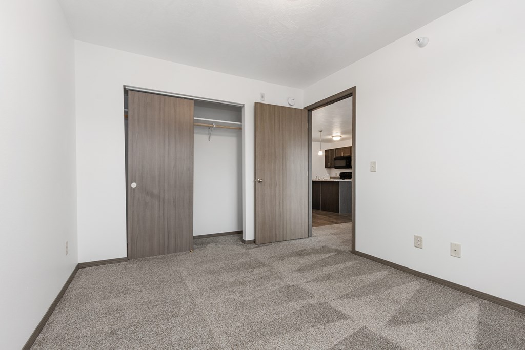 A room with a carpeted floor and two doors.
