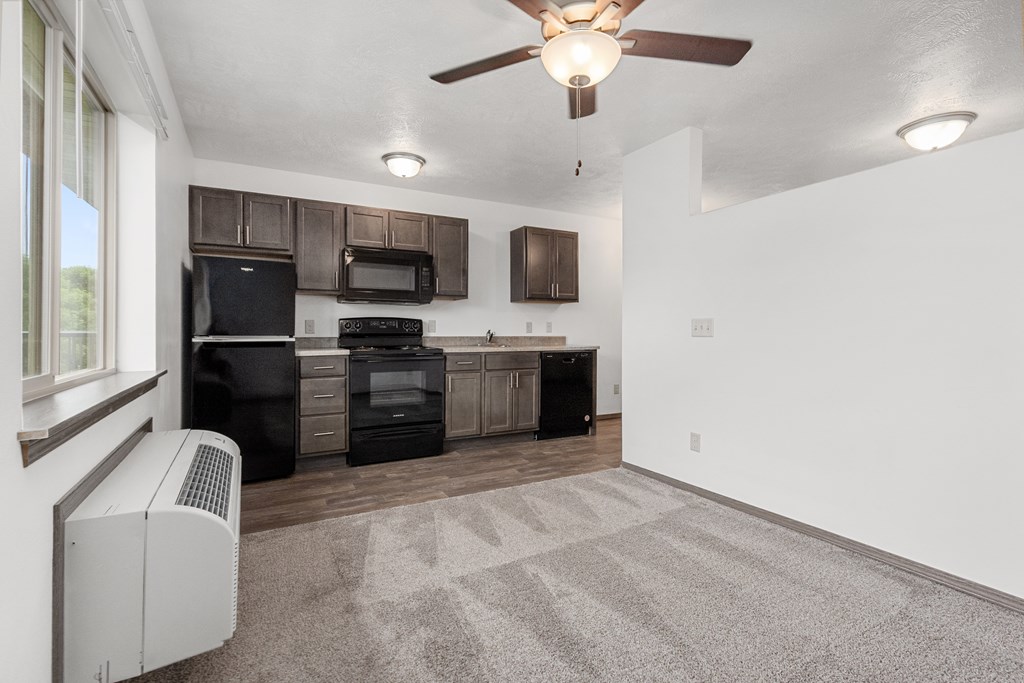 A kitchen with a black fridge, microwave, and oven.