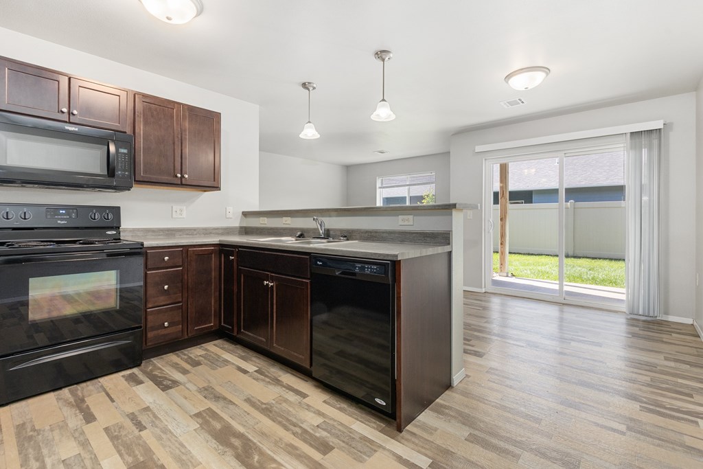 A kitchen with dark wood cabinets and black appliances.
