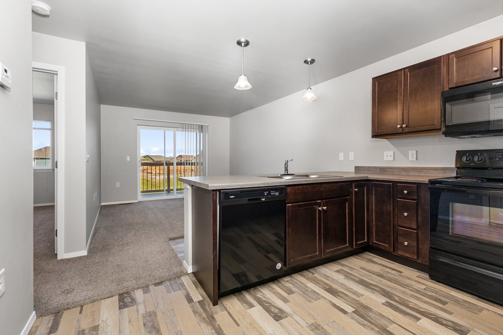 A kitchen with black appliances and wooden cabinets.
