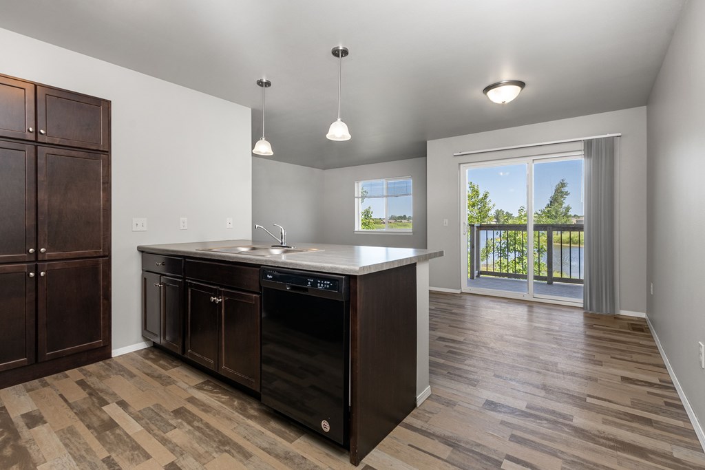 A kitchen with a black dishwasher and wooden cabinets.