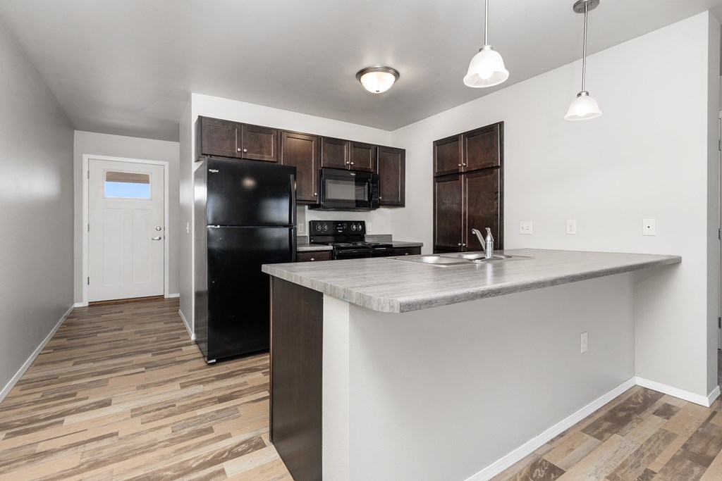 A kitchen with a black fridge and microwave.