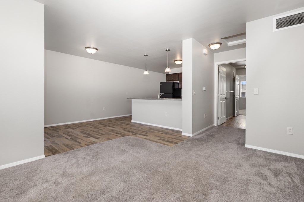 A spacious living room with a grey carpet and white walls.