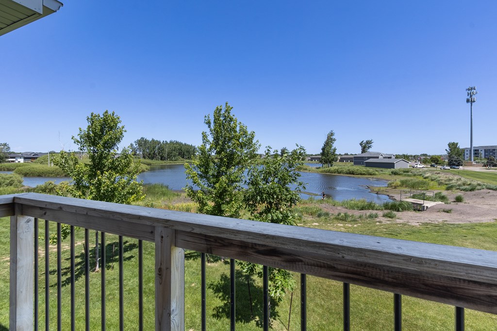 A balcony overlooks a river and a field.