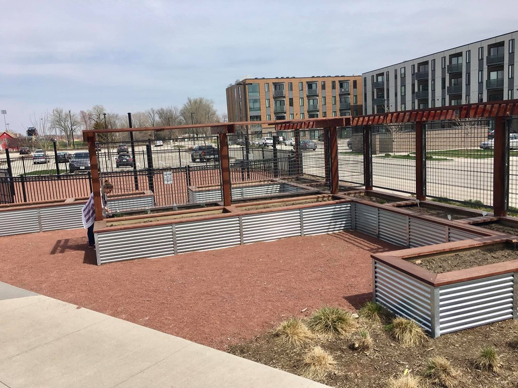 a community garden in a fenced in area with a building in the background