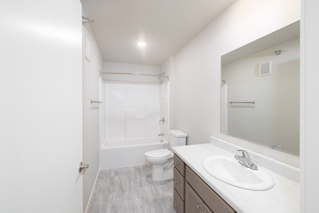 A white bathroom with a toilet, sink, and mirror.