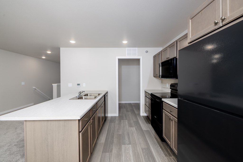 A modern kitchen with a black refrigerator and wooden cabinets.