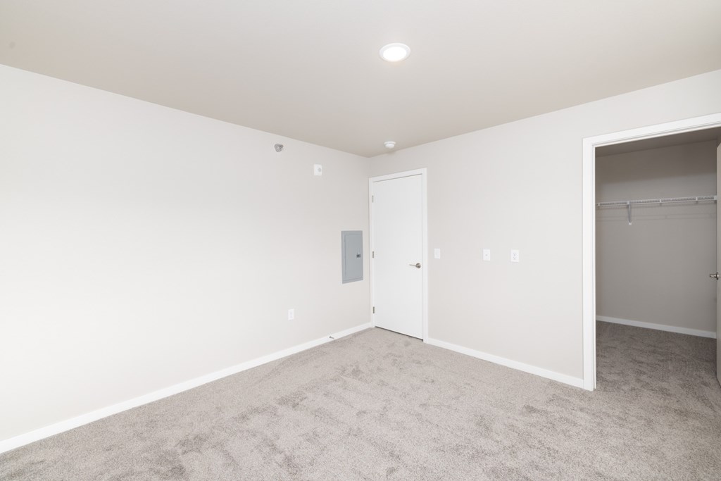 A room with a carpeted floor and a door on the left side.