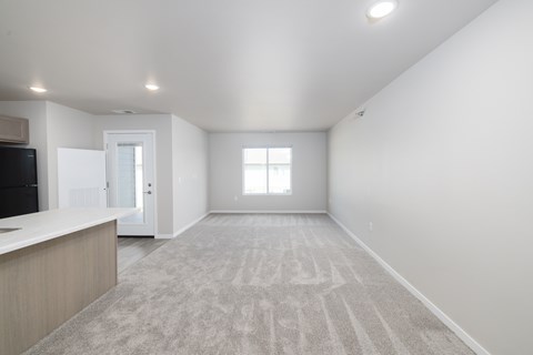 A spacious, empty room with a carpeted floor and a window.