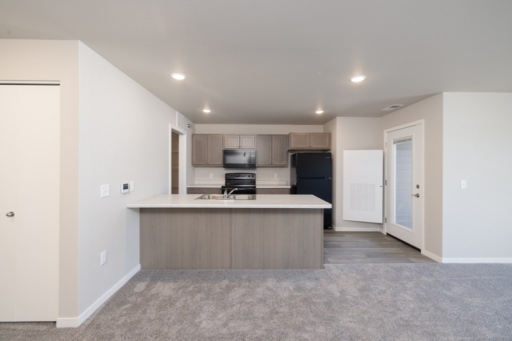 A kitchen with a white countertop and a black refrigerator.