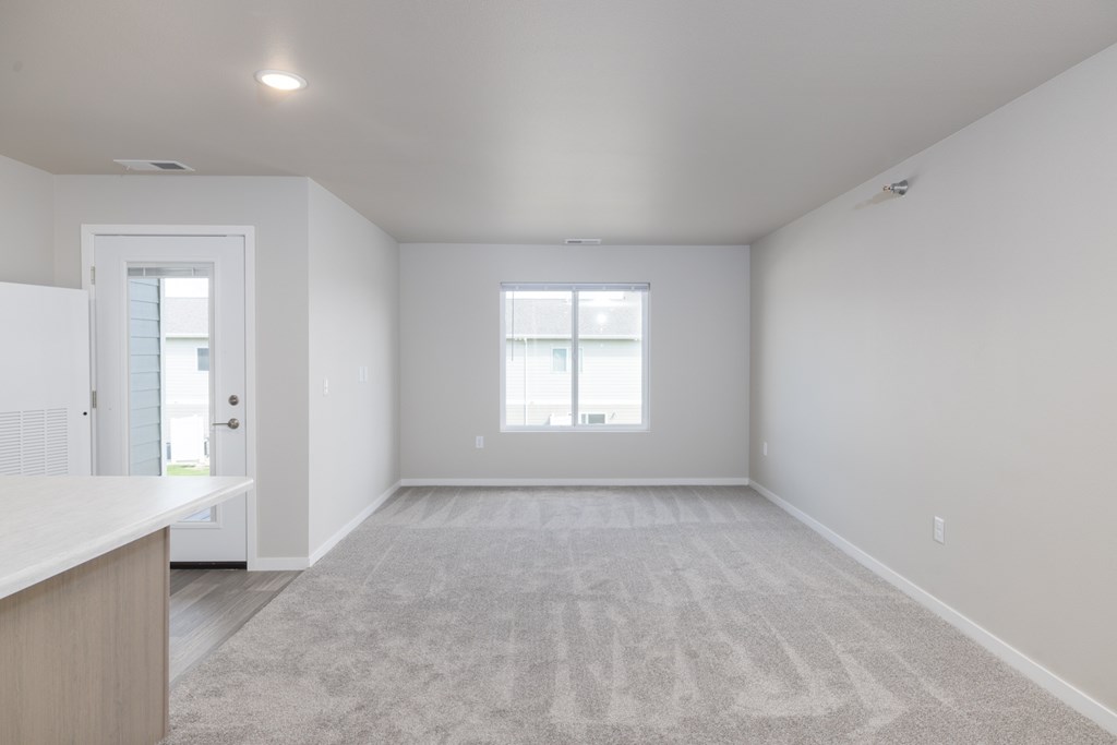 A spacious room with a carpeted floor and a window.