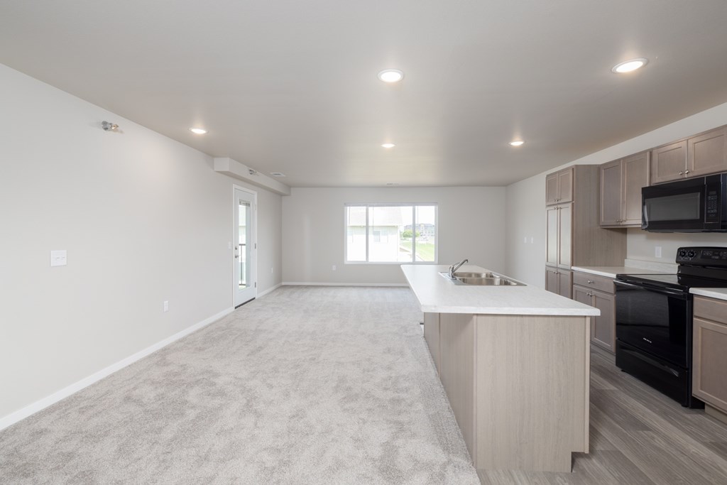A spacious kitchen with a white countertop and wooden cabinets.