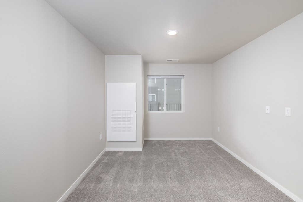 A room with a carpeted floor and a window with a balcony.