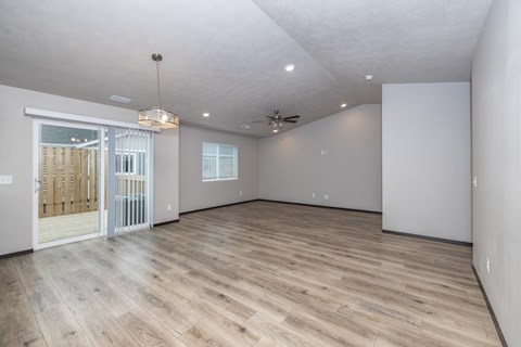 A spacious room with wooden flooring and white walls.