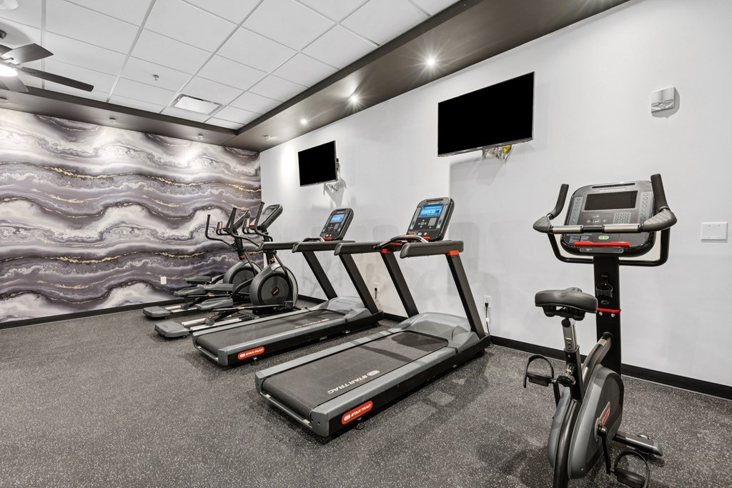 A gym with treadmills, exercise bikes, and a television.
