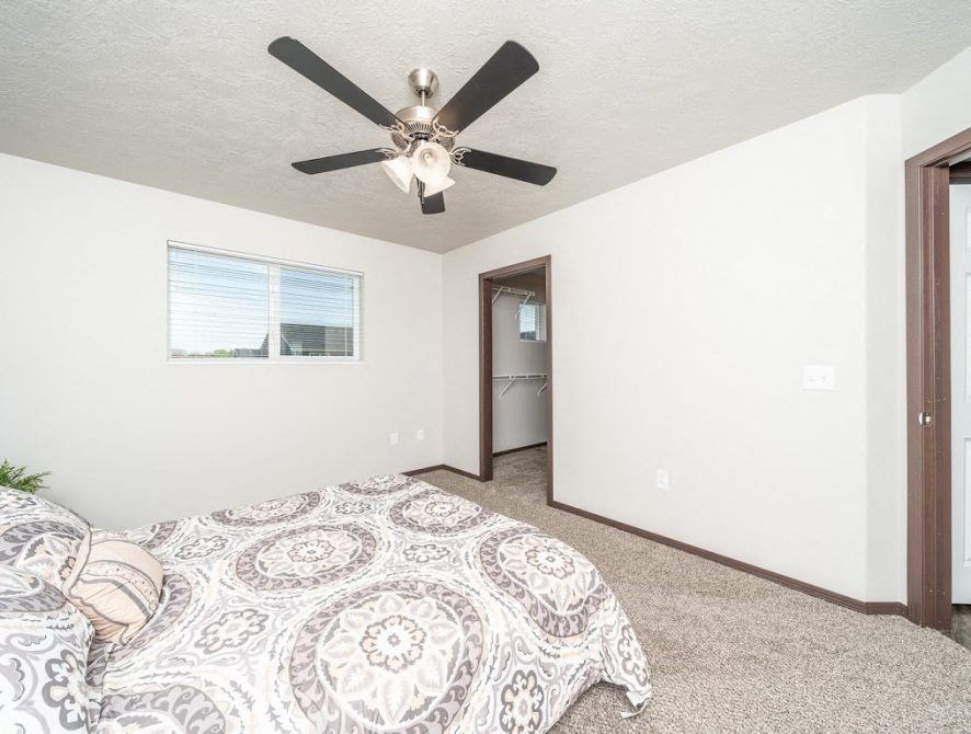 a bedroom with a bed and a ceiling fan