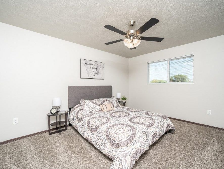 a bedroom with a bed and a ceiling fan