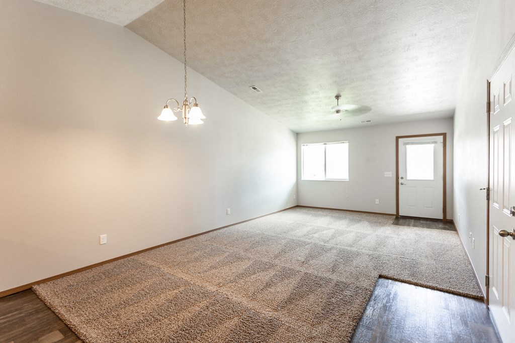an empty living room with a rug and white walls