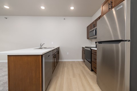 A modern kitchen with a stainless steel refrigerator and wooden cabinets.