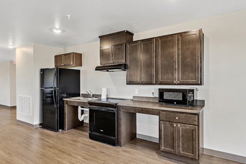 a kitchen with wooden cabinets and a counter top with a refrigerator and a microwave