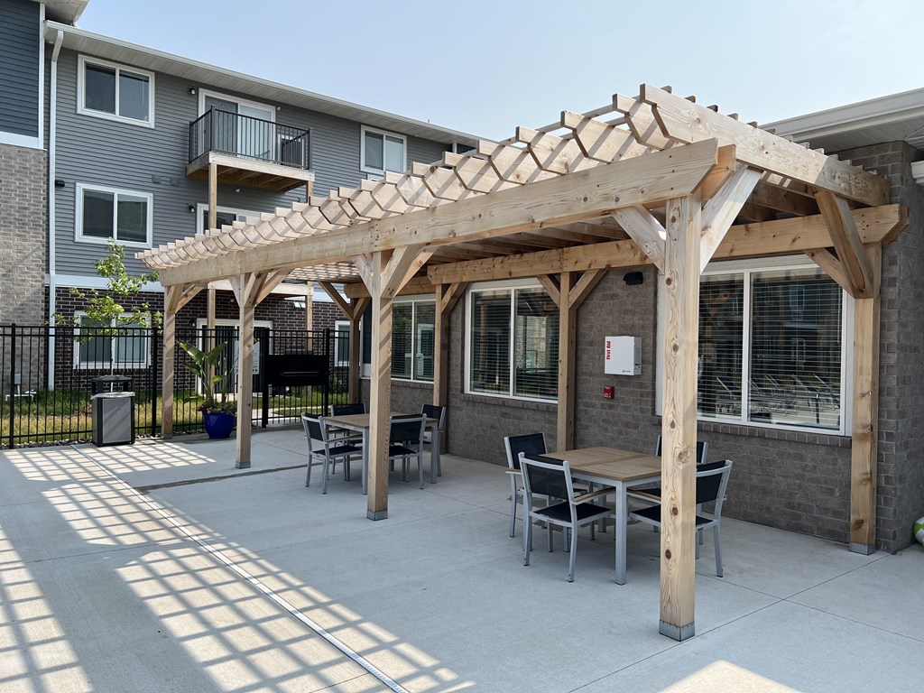 a patio with a wooden pavilion with tables and chairs