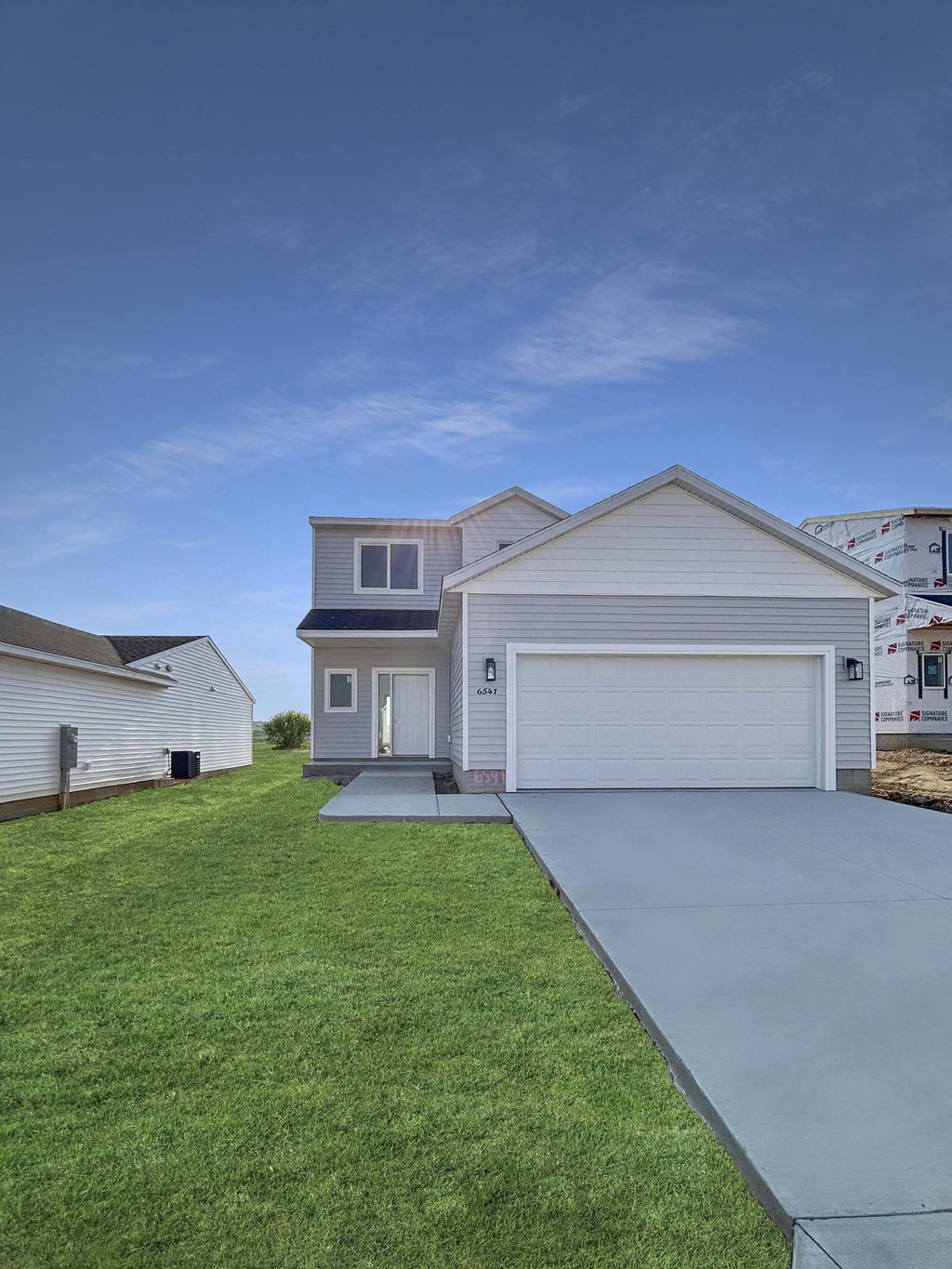a white house with a driveway and a lawn