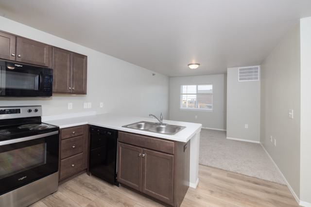 A kitchen with a stove, microwave, and sink.