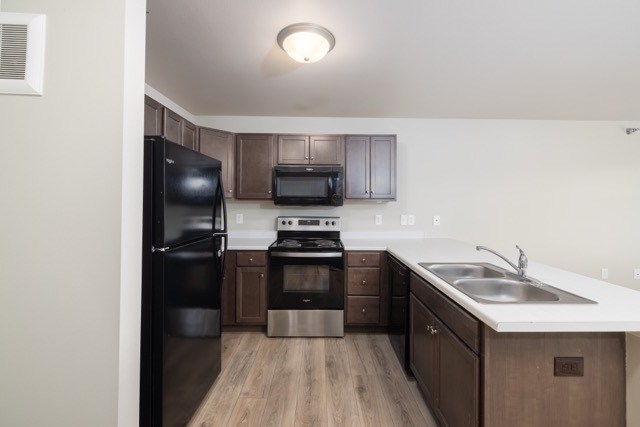 A kitchen with a black refrigerator, stove, and microwave.